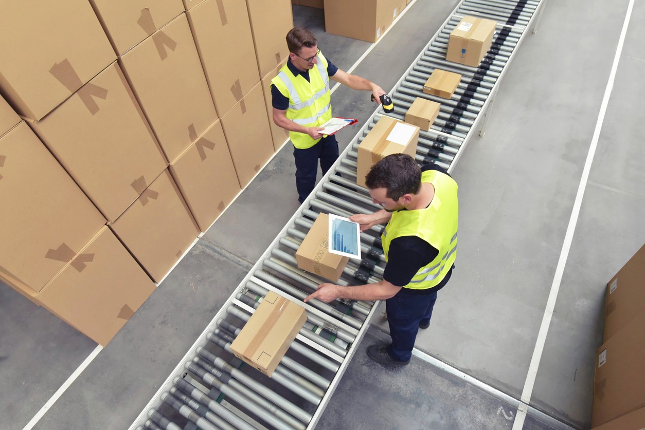 Two men working in a warehouse with a conveyor system